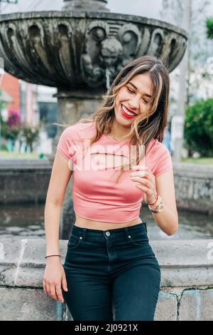 sorridente giovane donna latina attraente con i suoi lunghi capelli biondi, indossa il trucco con labbra rosse e ombre, moda e bellezza Foto Stock