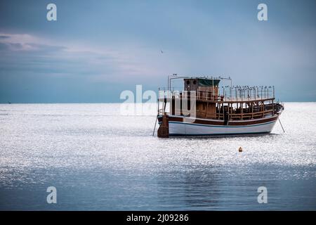 Bella nave in legno, ancorata al largo della costa di Rovigno, Croazia, contro il mare Adriatico aperto, coperta da gregge di gabbiani che prendono il rifugio per Foto Stock