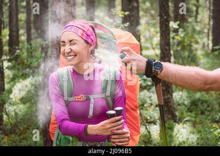 Un'escursionista femminile spruzza un aerosol per proteggere da insetti e zecche che aspirano sangue, portatori di malattie pericolose e parassiti. Sul sentiero nel Foto Stock