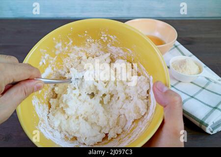 Mescolare a mano il composto in un recipiente con un cucchiaio per cuocere il pane brasiliano al formaggio Foto Stock