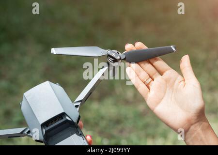 La mano tiene la pala dell'elica del drone. Sfumature tecniche di utilizzo e volo su UAV Foto Stock