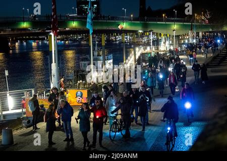 Brema, Germania. 17th Mar 2022. I partecipanti ad una catena di luci d'azione formano una catena di luci sulle rive del Weser. Le stazioni di radio Bremen hanno chiesto la partecipazione a "la nostra luce per la fiducia" per dare un segno di speranza e di pace. Credit: Sina Schuldt/dpa/Alamy Live News Foto Stock