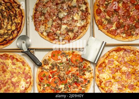 Pizze assortite con taglierine per pizza su scatole di consegna a domicilio Foto Stock