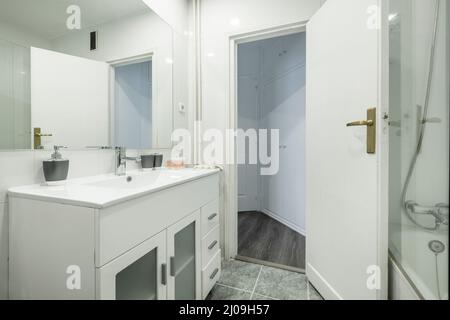 Bagno con lavandino e lavandino in resina bianca, specchio rettangolare senza cornice e box doccia con schermo Foto Stock