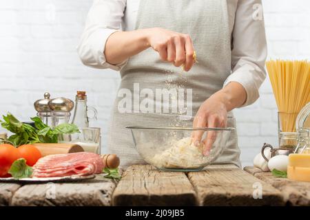 Chef professionista prepara pasta per la cottura della pasta alla carbonara. Piatto tradizionale italiano su sfondo bianco. Concetto di processo di cottura. Movimento congelato. Foto Stock