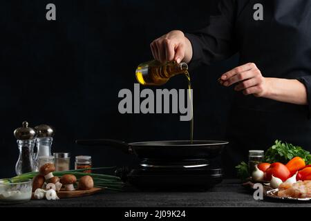 Lo chef professionista versa l'olio in una padella per preparare il ripieno di carne per la torta. Ingredienti per cucinare sullo sfondo. Spazio su sfondo blu scuro. Foto Stock