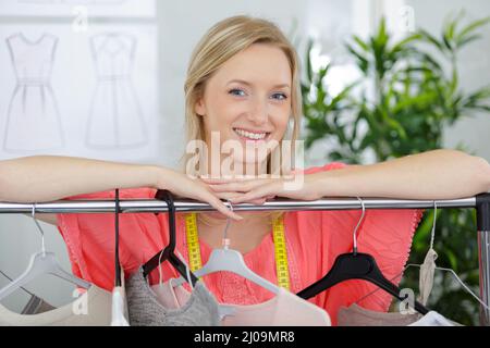 bella bionda guardando attraverso la barra dei vestiti nel negozio Foto Stock