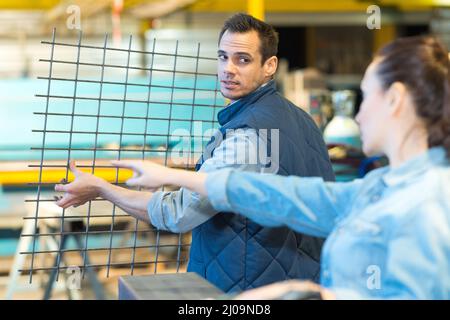 operatore di fabbrica che trasporta un foglio di griglie di metallo Foto Stock