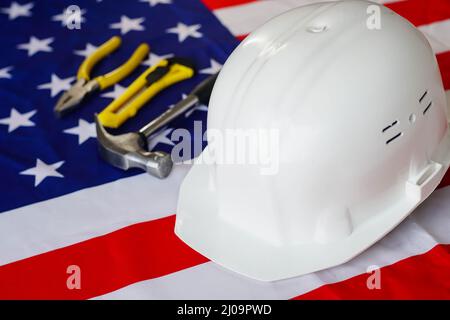 Bandiera USA con casco e strumenti di costruzione. Buon giorno del lavoro. Foto Stock