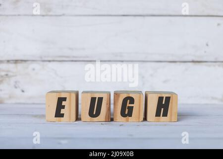 Concetto Eugh scritto su cubi o blocchi di legno, su sfondo bianco di legno. Foto Stock