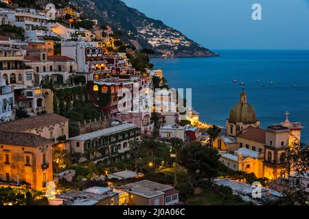 Vista al tramonto della Chiesa di Santa Maria Assunta e delle case di Positano lungo la Costiera Amalfitana, la Provincia di Salerno, la Regione di Compania, Italia Foto Stock