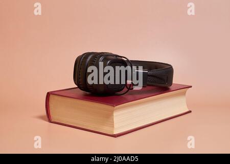Audiolibro. Le cuffie giacciono su un libro su uno sfondo colorato Foto Stock