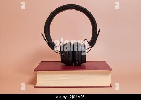 Audiolibro. Le cuffie si trovano su un libro su uno sfondo colorato Foto Stock
