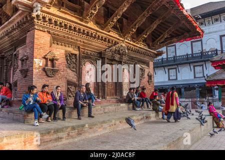 Giovani seduti sui gradini di un tempio in piazza Durbar a Kathmandu, Nepal Foto Stock