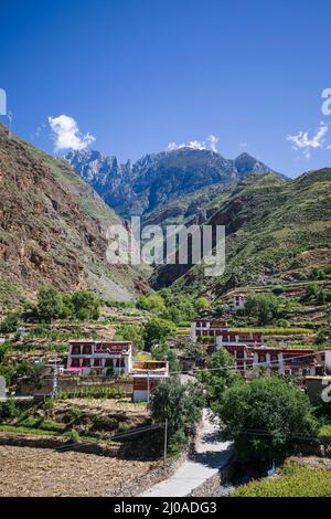 Villaggio tibetano visto dall'alto in una valle con cielo blu Foto Stock