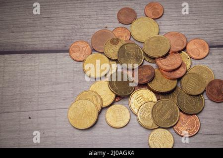 Una collezione di monete in euro in parte molto utilizzate su una superficie di legno Foto Stock