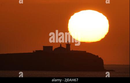 Il sole sorge dietro il Faro di Farne, costruito all'inizio del 19th secolo sulla punta meridionale delle isole Farne interne nel Northumberland. Data foto: Venerdì 18 marzo 2022. Foto Stock