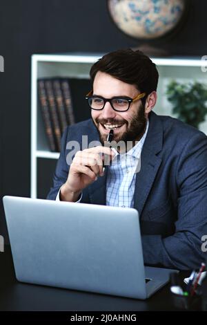 Ive ha ottenuto solo l'idea.... Scatto corto di un giovane uomo d'affari seduto di fronte a un portatile e pensando in un ufficio moderno. Foto Stock