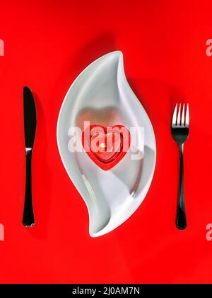 Candela su piastra bianca e sfondo rosso Foto Stock