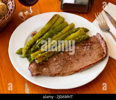 Bistecca di manzo appetitosa con asparagi sul piatto Foto Stock