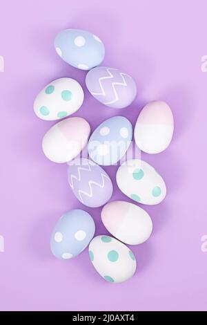 Vista dall'alto di un gruppo di uova di pasqua color pastello su sfondo viola Foto Stock
