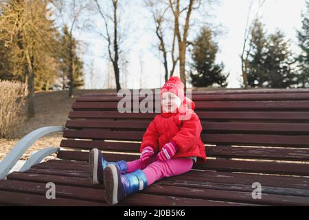 ragazza felice in stivali e giacca rossa. divertente ragazza allegra bambino giocare all'aperto Foto Stock