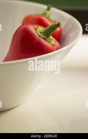 Peperoni freschi crudi nel piatto Foto Stock