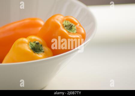 Peperoni freschi crudi nel piatto Foto Stock