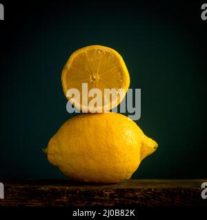 Limoni freschi impilati su una superficie in legno su uno sfondo scuro Foto Stock