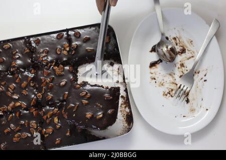 Fetta di torta di Texas servita su un piatto. Torta di burro e cioccolato tagliata a pezzi rettangolari all'interno del cestino da forno e tagliata a pezzi da esso. Shot o Foto Stock