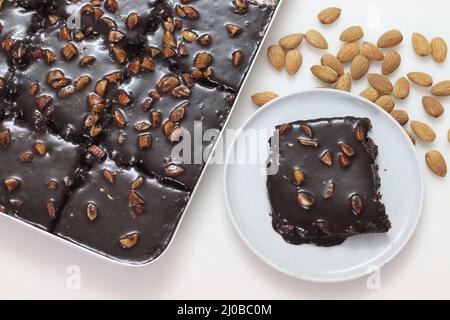 Fetta di torta di Texas servita su un piatto. Torta di burro e cioccolato tagliata a pezzi rettangolari all'interno del cestino da forno e tagliata a pezzi da esso. Shot o Foto Stock