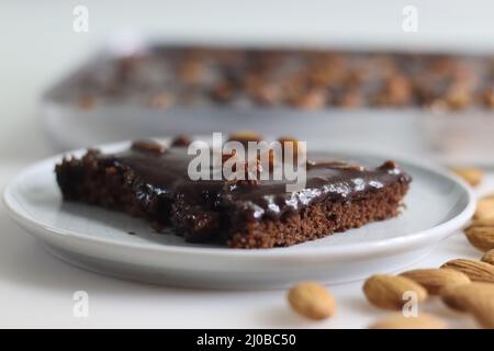 Fetta di torta di Texas servita su un piatto. Torta di burro e cioccolato tagliata a pezzi rettangolari all'interno del cestino da forno e tagliata a pezzi da esso. Shot o Foto Stock