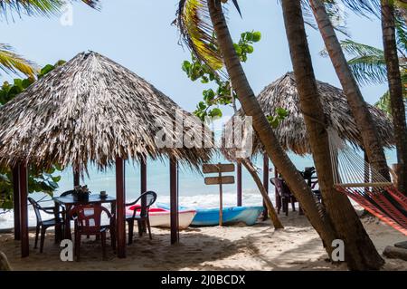 Due capanne con tavoli sedie e amaca presso la spiaggia di sabbia bianca di fronte il mare dei Caraibi Foto Stock