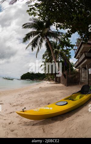 Kayak giallo recante sulla spiaggia di sabbia con Palm tree Foto Stock