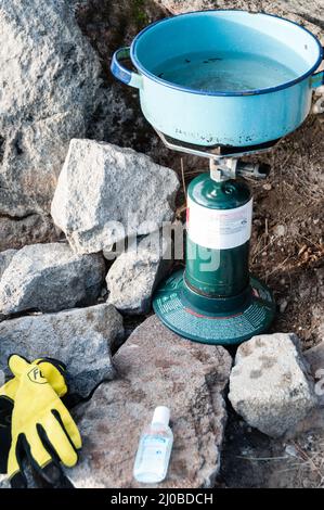 Acqua bollente con fornello da campeggio nel mezzo di grandi rocce e pietre in montagna Tajamulco Foto Stock