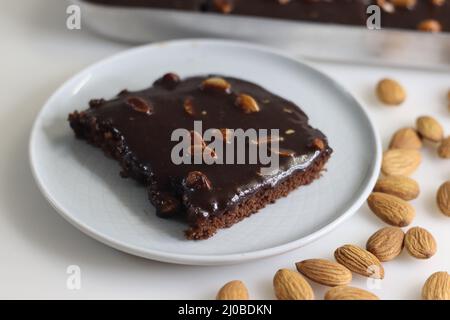 Fetta di torta di Texas servita su un piatto. Torta di burro e cioccolato tagliata a pezzi rettangolari all'interno del cestino da forno e tagliata a pezzi da esso. Shot o Foto Stock