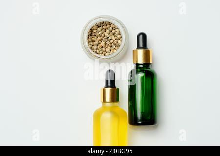 Prodotti cosmetici marijuana, olio CBD. Estratto di canapa medicinale in bottiglie cosmetiche su sfondo bianco. Cura naturale delle erbe, uso medico, cannabis Foto Stock