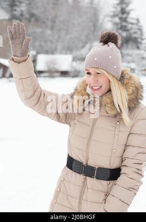 Una bella giovane donna in piedi in un paesaggio invernale e di un saluto Foto Stock