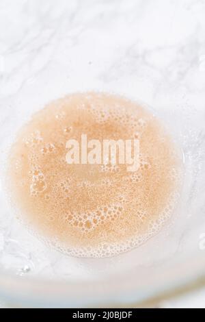 Attivare il lievito secco in un recipiente grande per la miscelazione del vetro per preparare la pasta per pizza. Foto Stock