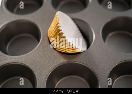 Foderare la teglia per cupcake con i rivestimenti per cupcake in lamina per cuocere i cupcake di pan di zenzero. Foto Stock