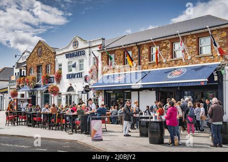 Dublino, Irlanda, ago 2019 persone godersi il bel tempo in Howth ristoranti all'aperto. Pier Street con pub, ristoranti e negozi popolare posizione turistica Foto Stock