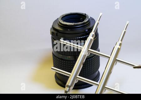 Obiettivo della fotocamera con chiave in metallo per la pulizia dell'obiettivo su sfondo bianco Foto Stock