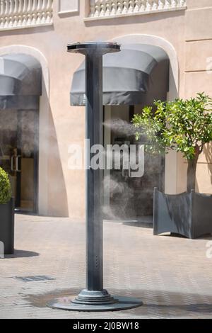 Gli sprinkler spruzzano acqua vaporizzata in strada per raffreddare la temperatura calda estiva Foto Stock