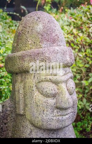 Primo piano faccia del idolo di pietra (Dolharubang, le pietre del nonno) vicino a Jeju strada pedonale, Foto Stock