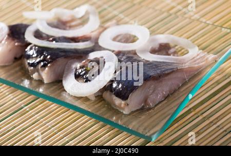 Aringa salata con cipolla su sfondo di bambù Foto Stock