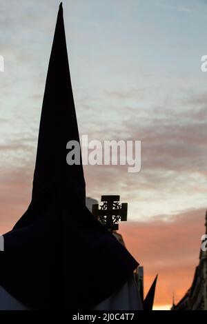 Vista al tramonto di un Nazareno con cappuccio in una processione pasquale per le strade di Madrid. Foto Stock