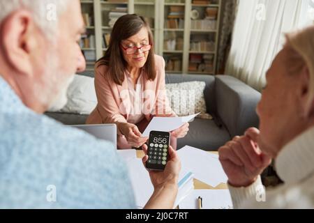 Coppia anziana con calcolatore che pensa all'offerta per risparmiare i soldi in una consultazione finanziaria Foto Stock
