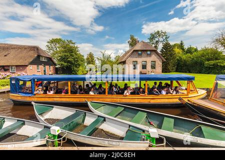 GIETHOORN, PAESI BASSI - 26 LUGLIO 2016: I turisti si godono una crociera sui canali con una barca di legno nel famoso villaggio olandese di Giethoorn, l'Olanda Foto Stock