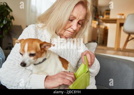 Donna anziana con cane piccolo preoccupato guardando in borsa vuota come concetto di povertà in vecchiaia Foto Stock