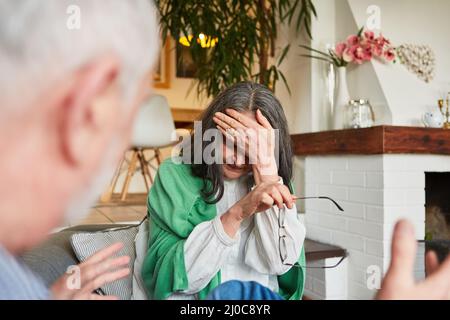 Coppia anziana che litigano l'uno con l'altro nel soggiorno come simbolo di gelosia o di conflitto di rapporto Foto Stock